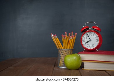 Back to school background on wooden table and blackboard on a background. Books, pencils, alarm clock and apple on desk. First time to school. Elementary school - Powered by Shutterstock