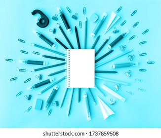 Back to school background with opened notepad and variety of school supplies in trendy aqua color. Flat lay. Close-up. Copy space. Mockup for your design.