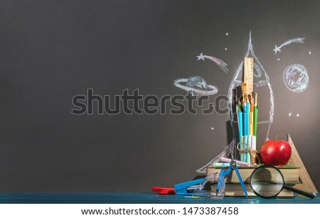 Back to school background. A rocket made of pens, pencils, crayons and brushes. Which are located at the spaceport from books.