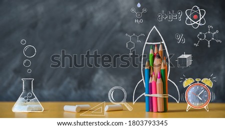 Back to school background with rocket made from pencils on chalkboard. Alarm clock, atom, chemistry