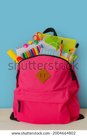 Back to school. Backpack for school or college with bright colorful school supplies on blue background. Stationery for school children's studies. Greeting card or banner for sale. Vertically