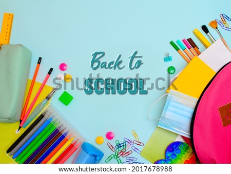 Back to school. Backpack for school or college with bright colorful school supplies on light blue background. Stationery for school children's studies. Greeting card. Flatlay
