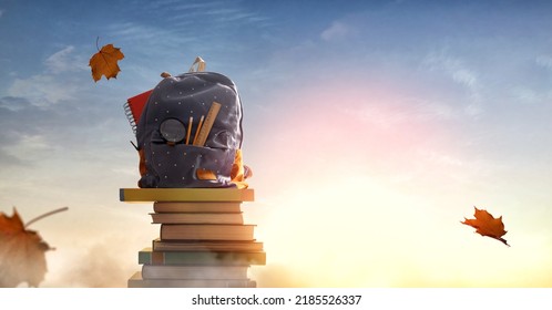 Back to school! Backpack is standing on the tower of books on background of sunset sky. Concept of education and reading.