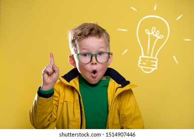 Back to school. Blond child in yellow raincoat and green glasses with light bulb. Funny child with open mouth and finger pointed up. Genius kid with bulb. Success, idea, win and innovation technology - Shutterstock ID 1514907446
