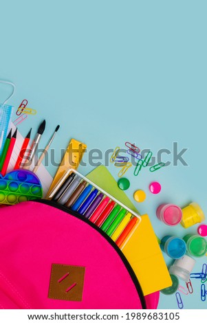 Back to school. Bright colorful school supplies and backpack for school or college on blue background. Stationery for school children's studies. Greeting card or banner for sale. Copyspace. Vertically