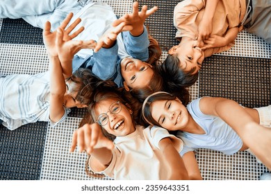 Back to school. Cheerful schoolchildren lying on the floor and smiling at the camera, top view. Education and science concept. - Powered by Shutterstock