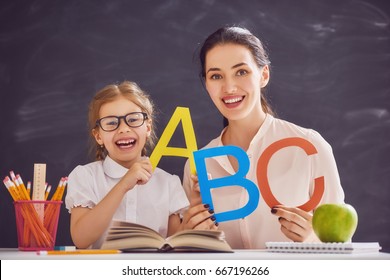 Back To School! Child Is Learning To Write. Adult Woman Teaches Child The Alphabet.