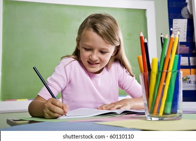 Back To School - Close-up Of 8 Year Old Girl Writing In Notebook In Classroom