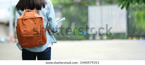 Back to school, Back of\
college student with backpack while going to university by walking\
from street, teenager in campus, education background, banner\
concept