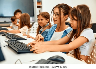 Back to school. Computer science lesson in a modern classroom. Schoolchildren sitting at computers and listening to the teacher. Education and science concept.