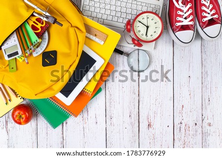 Back to school concept. Backpack with school supplies. Top view. Wooden background. Copy space.
