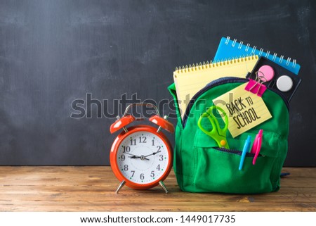 Back to school concept with bag backpack and school supplies  over chalkboard background