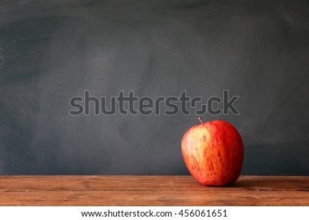Back to school concept. Blackboard with apple on wooden desk. retro filtered
