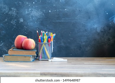 Back to school concept with colorful school supplies with aaple friuts on blackboard background with copy space on blackboard