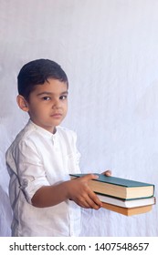 Back to school concept. Cute middle eastern boy holding a stack of books against the white background. Portrait of Central Asian kid preparing to go to school. Vetical photo