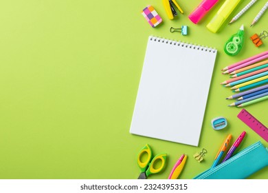 Back to school concept. Empty notepad with school stationery on green background.