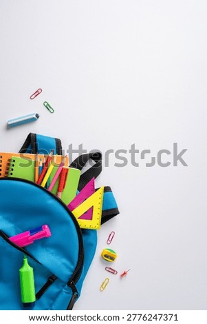 Back to school concept featuring a blue backpack filled with colorful stationery, pencils, notebook and rulers arranged in a clean flat lay ideal for education, study and school marketing