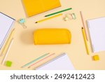 Back to school concept. Flat lay top view on full pencil case with pencils and pens with notebook isolated on yellow background with empty space for text