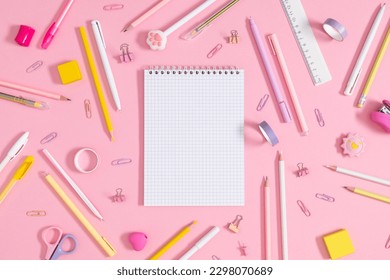 Back to school concept. Flat lay top view of scattered stationery notepad pens pencils paper clips  sticky tape note paper isolated on pastel pink background