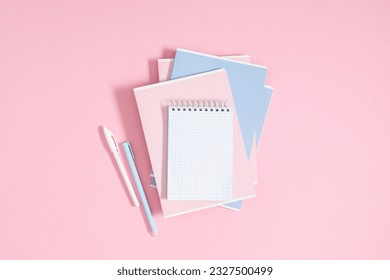 Back to school concept. Flat lay top view of stack of notepads with empty space for text, pens and pencil on isolated pastel pink background. - Shutterstock ID 2327500499