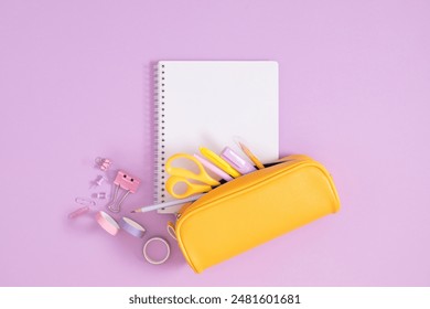 Back to school concept. Flat lay top view on full pencil case with pencils and pens with notepad isolated on pastel purple background. 