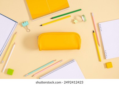 Back to school concept. Flat lay top view on full pencil case with pencils and pens with notebook isolated on yellow background with empty space for text - Powered by Shutterstock