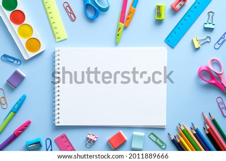 Back to school concept. Flat lay style composition with stationery and notepad on blue background. Top view, overhead