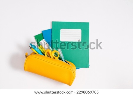 Back to school concept. Flat lay top view on school supplies stack notebook yellow full pencil case with pencils and pens notepad scissors isolated on white background