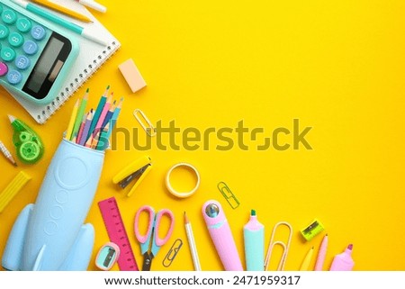 Back to school concept. Flat lay, top view colorful school supplies, rocket-shaped pencil case, calculator, notepad on yellow background.