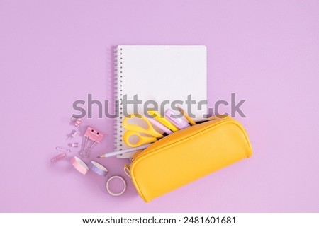 Back to school concept. Flat lay top view on full pencil case with pencils and pens with notepad isolated on pastel purple background. 