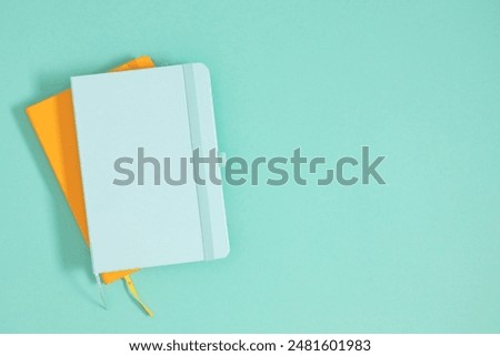 Back to school concept. Flat lay top view of stack of notepads, isolated on pastel mint background. 