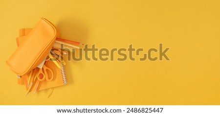 Back to school concept. Flat lay top view on full pencil case with pencils and pens with notebook isolated on yellow background with empty space for text