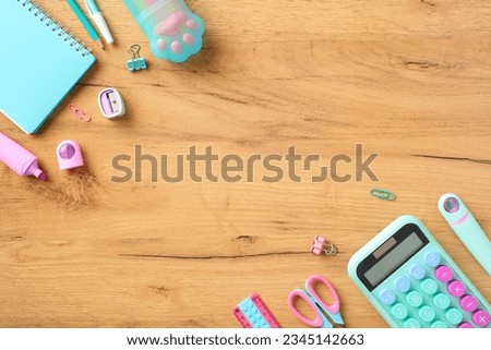 Back to school concept. Girls school supplies in pink and turquoise colors on wooden desk table. Top view.
