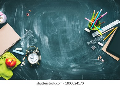 Back to school concept. Office supplies. Stationery on green blackboard background alarm clock, color chalks, pencil, apple, notebook. Copy space. Top view. Flat lay. - Shutterstock ID 1803824170