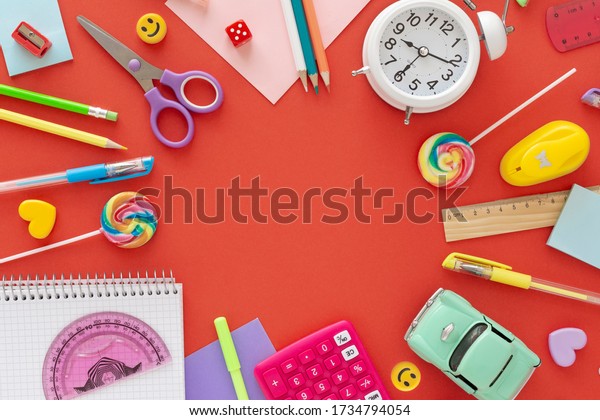 Back to school concept , online\
education , parenting, stay home .on a coral background alarm\
clock, toy car,  pens , pencils, candies. Flatly, copy space\
.