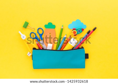 Back to school concept. Pencil case with school stationery on a yellow background. 