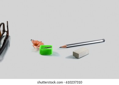 Back to school concept- a Pencil,erasor, sharpner an cut slice of the pencil on white table with or without spectacles not properly aranged isolated.