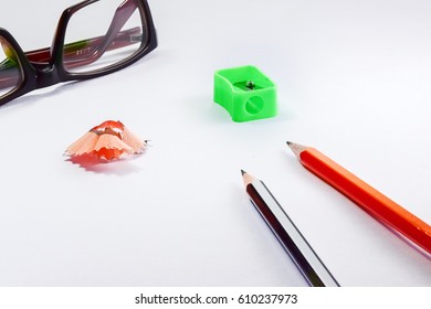 Back to school concept- a Pencil,erasor, sharpner an cut slice of the pencil on white table with or without spectacles not properly aranged isolated.