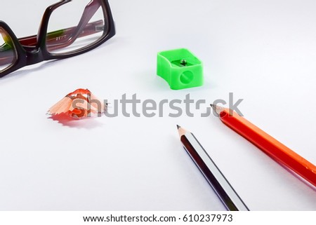 Back to school concept- a Pencil,erasor, sharpner an cut slice of the pencil on white table with or without spectacles not properly aranged isolated.
