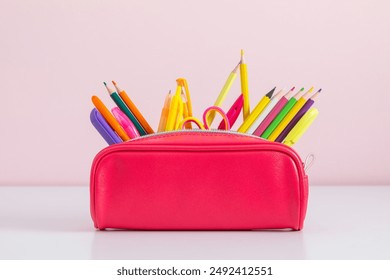 Back to school concept. Pink full pencil case with pencils and pens, scissors, school supplies isolated on against background of pink wall with empty space.  - Powered by Shutterstock