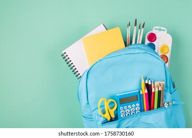 Back To School Concept. Top Above Overhead View Photo Of Full Blue Backpack Filled With School Stationery Isolated On Turquoise Background