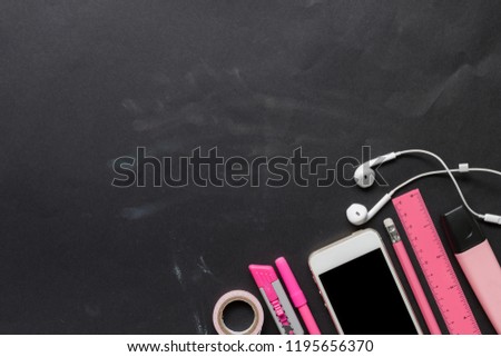 Back to school concept. Top view of educational supplies, pencil, pen, marker pen, smartphone, earphone, ruler, cutter knife on black background with copy space.