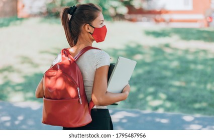 Back To School Concept. University Student Wearing Mask Walking On Campus With Backpack, Books And Laptop. 