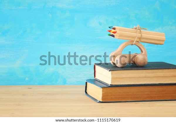 Back to school concept. Wooden toy\
car with colorful pencils on the roof over stack of\
books.
