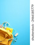 Back to school concept. Yellow backpack with colorful school supplies on vibrant blue background.