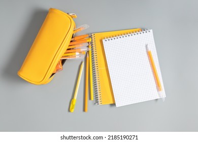 Back to school concept. Yellow school pencil case with filling school stationery, notebook, pens, pencils. Yellow school accessories on grey background. Flat lay, top view, copy space - Powered by Shutterstock