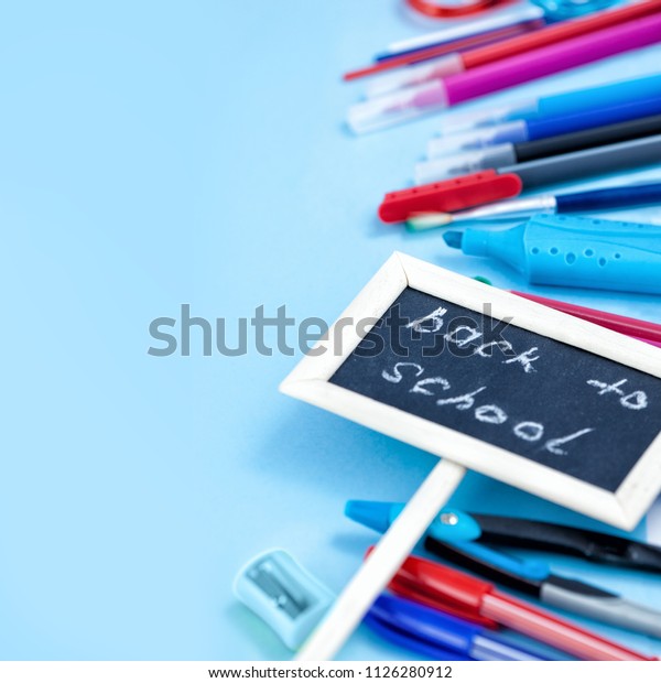 Back to School Conceptl: Notebook and School\
Supplies. Notebook, Bookmark, Pen, Pencils,  Scissors, Felt Pens,\
Marker on the Blue Background. Backgroung in Blue, Red and White\
Colors.