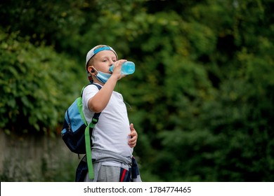 Back To School. Cool Little Schoolboy Drinking Water. Boy Wearing A Face Mask Down