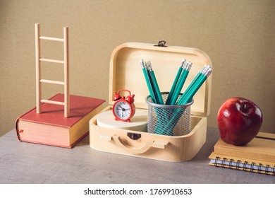 Back to school creative concept with pencils, apple, books and suitcase box. Modern still life composition - Powered by Shutterstock