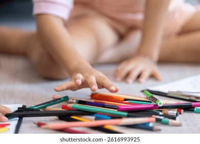 Back to School and Creative Exploration. A young girl reaches for colored pencils during a fun activity.